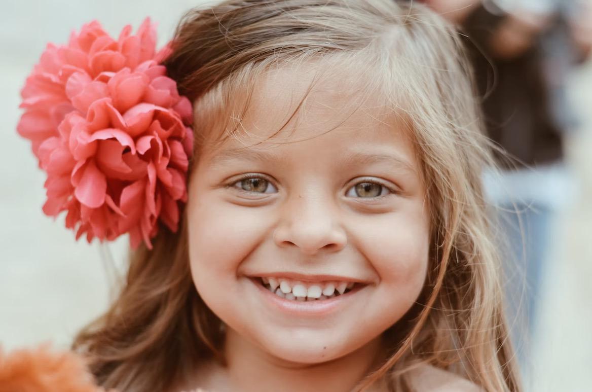 Young girl smiling with flower flower in her hair.